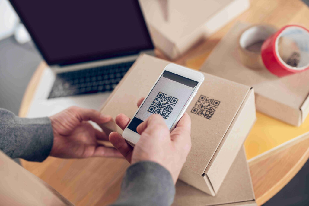 Cropped photo of an Internet shop worker holding his smartphone over the closed cardboard box